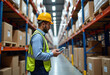 © Valentina Zaitseva - Manager wearing hard hat with digital tablet counts merchandise in warehouse. He walks through rows of storage racks with merchandise.