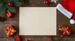 © Dual Studio - High angle view of empty letter on wooden table with christmas decoration. Top view of empty xmas wish list with little gift present and santa claus hat on wooden background.