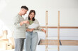 © Pixel-Shot - Young couple with instructions assembling shelving unit in bedroom on moving day
