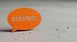 © Mirivox - Orange speech bubble with cut-out word strategy, placed on a concrete surface. Represents strategic planning, business, and communication