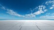 © Valentyna Prudnikova - Expansive concrete floor meets infinite blue sky with soft white clouds, creating a minimalist landscape of geometric precision and ethereal openness
