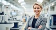 © vadosloginov - Young professional woman smiling confidently in a modern manufacturing facility