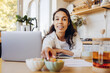 © Maria Vitkovska - Confident African American woman working at home in modern kitchen taking dessert, having break