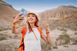 © EdNurg - Happy hiker taking a selfie with smartphone while hiking in the desert mountains