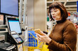 © Iryna - Senior woman scanning wooden item at self checkout terminal