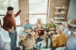 © deagreez - Funny toast at a warm family gathering as the host invites comfort and laughter during a big Thanksgiving dinner at home