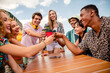 © deagreez - Group of diverse friends enjoying a fun outdoor gathering bonding over drinks and laughter in a bright city setting