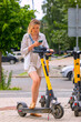 © Nobilior - woman using smartphone while standing near electric scooter on city street