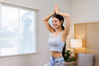 © David - A young woman practices a fitness exercise on a yoga mat in her living room. She stretches in a bright apartment, promoting a healthy lifestyle and physical activity. Yoga concepts