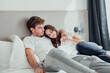 © Daniel - A young couple lies in bed, embracing and talking quietly. Their smiles and gentle touches show comfort, closeness, and love, sharing a peaceful moment in their cozy home.