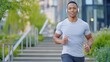 © acnaleksy - focused man running up concrete stairs in a modern urban park, with headphones in and a determined expression on his face