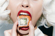 © VICHIZH - Young woman with bold makeup and blonde curls holding sushi close to her mouth, showcasing vibrant colors and a playful expression.
