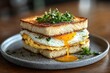 © keke - Close-up of a toasted sandwich with fried egg and fresh green herbs, showing a runny yolk dripping onto a gray ceramic plate