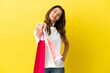 © luismolinero - Middle aged caucasian woman isolated on yellow background holding shopping bags and giving them to someone