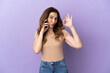 © luismolinero - Middle aged caucasian woman using mobile phone isolated on purple background showing ok sign with fingers