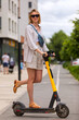 © Nobilior - woman riding on electric scooter on city street