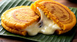 © Visions of Diversity - Colombia Pumpkin Arepas (Arepas de Auyama). Colombian pumpkin arepas with cheese filling on banana leaf, golden crust and melted cheese