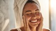 © mila103 - A joyful woman applies cleanser to her face radiating happiness and glow in a sunlit bathroom.