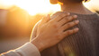 © Athichai - Cropped shot showing a friend’s hand resting on another person’s shoulder, expressing empathy and encouragement, natural daylight, shallow depth of field
