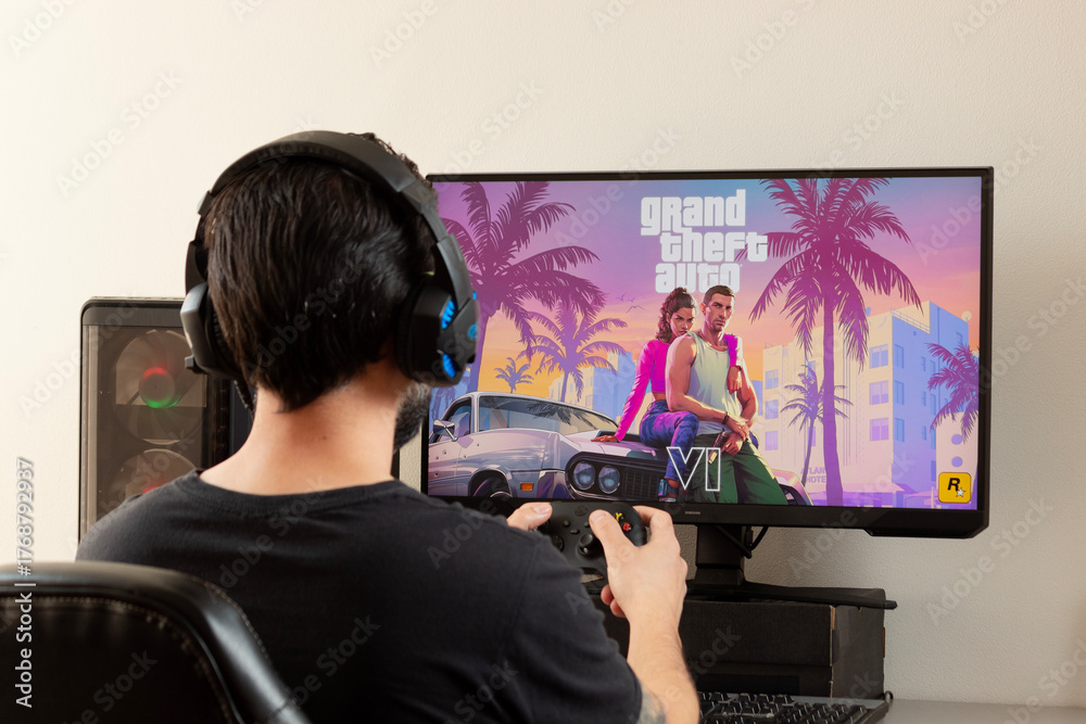 A young male gamer holding a xbox controller and using gamer earphones ...