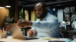 © DC Studio - Black business consultant putting adhesive note on laptop screen as a memo, trying to remember a task from his to do list. Working late and leaving a reminder for next morning.