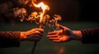 © Aldiwftr - Close-up of two hands, one holding a burning torch and the other reaching out to touch the flames against a dark background with warm tones.