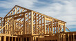 © MYS Design - Close-up of a new residential home construction site showing the wood framing, rafters, and structure against a partly cloudy sky