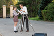 © Vagengeim - Teacher assists a girl in attaching the telescope mount onto a tripod outdoors, highlighting teamwork, practical guidance, and interest in astronomy learning