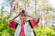 © Halfpoint - Elderly woman photographing nature during forest walk.
