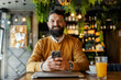 © Dusan Petkovic - Portrait of smiling business casual man sitting in cafeteria with cellphone in hands and looking at the camera.