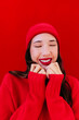 © VISTA by Westend61 - Smiling portrait of woman with red beanie and sweater against monochrome red