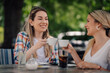 © Ljustina - Two smiling women toasting with coffee cups at outdoor cafe