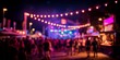 © Rifqi - Blurred crowd enjoying a vibrant night festival with bright stage lights and string lights overhead, concept for music events, outdoor celebrations and summer parties