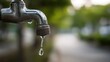 © ปฏิภาน ผดุงรัตน์ - Water dripping from an old metal faucet in the backyard with a blurred green background, emphasizing the importance of water