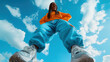 © SnapVault - Young black woman expressing joy and confidence, wearing colorful streetwear clothing with sneakers, viewed from a low angle against a vibrant blue sky with white clouds