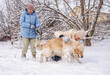 © StockMediaSeller - Elderly woman and her adult daughter playing with a Golden Retriever in the snow. The daughter pets the cheerful dog while the mother holds the leash and smiles, enjoying a joyful winter moment