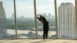 © BESTIMAGE - banner woman stretching office exercising standing on empty modern office window skyscraper floor. workplace health relief shoulder physical problem muscle stress pain on skyscraper view city river.