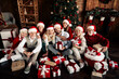 © deagreez - Family gathers for Christmas joy with Santa hats presents and a decorated tree in a cozy home setting