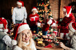 © deagreez - Family Christmas celebration around a festive table with Santa hats gifts and warm lights in a cozy home setting
