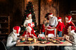 © deagreez - Family Christmas celebration around a festive dining table with a decorated tree and Santa hats creating warm holiday atmosphere