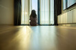 © shine - Moving day. Woman sitting on floor in new apartment. Sunlight streams in, creating a warm and inviting atmosphere in the serene indoor setting. Empty large room with laminate flooring. Copy space