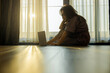 © shine - Concentrated businesswoman using laptop while sitting on floor with serene morning light filters through sheer curtains, large windows and a warm atmosphere. Enjoy carefree rest and optimistic mood