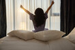 © shine - Back side of Middle aged woman waking up in morning, Stretches and gets out of bed, Bright sunlight from apartment window in bedroom, She is ready for Business opportunities, Achievements, Adventures