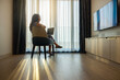 © shine - Middle aged woman with Blank screen laptop for presentation media of business watching TV. Sunlight through sheer curtains, casting shadows on wooden floor. The modern room creating serene atmosphere.