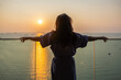 © shine - Businesswoman standing at balcony looking Beautiful view sunrise over sea, fresh air, getting ready for new day, Relax, Wake up, Thinking. Woman enjoying her holiday in luxury hotel or apartment.