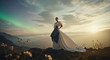 © SilhouetteStudioArt - Elegant woman in a wedding dress standing on a mountain peak with aurora borealis in the background at sunset