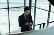 © amnaj - Asian businessman walking up stairs, smiling and typing on smartphone. Concept of corporate communication and mobile technology