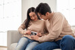 © tonefotografia - Expectant Couple Happily Shares Ultrasound Image in Cozy Living Room Setting