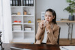 © amnaj - Asian businesswoman suffering from cold or flu, blowing nose with a tissue while sitting at her office desk