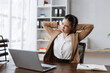 © amnaj - Businesswoman feeling discomfort and pain in her neck and shoulders while working on her laptop in a modern office